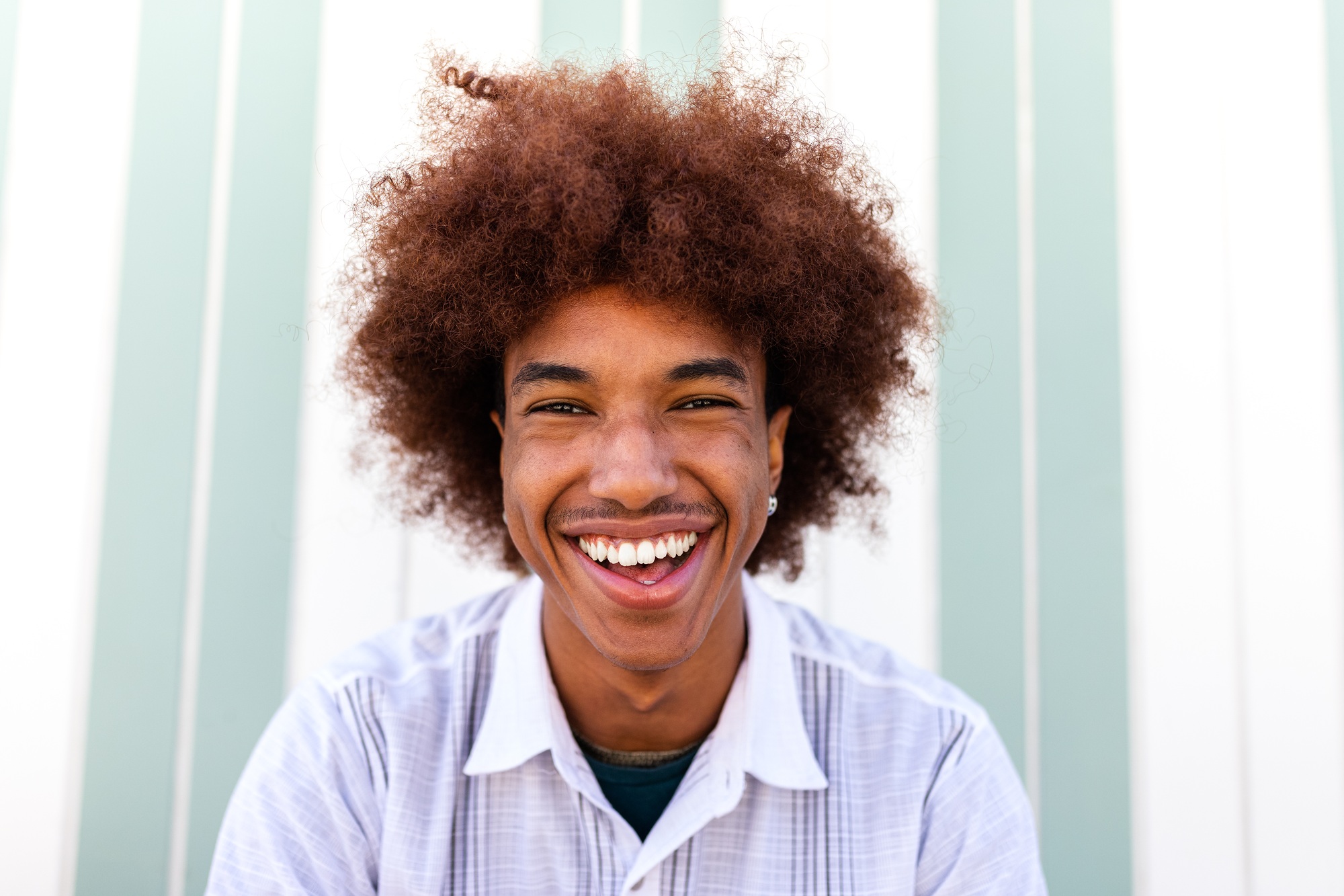 Headshot of happy African American Black young man smiling looking at camera. Summertime.