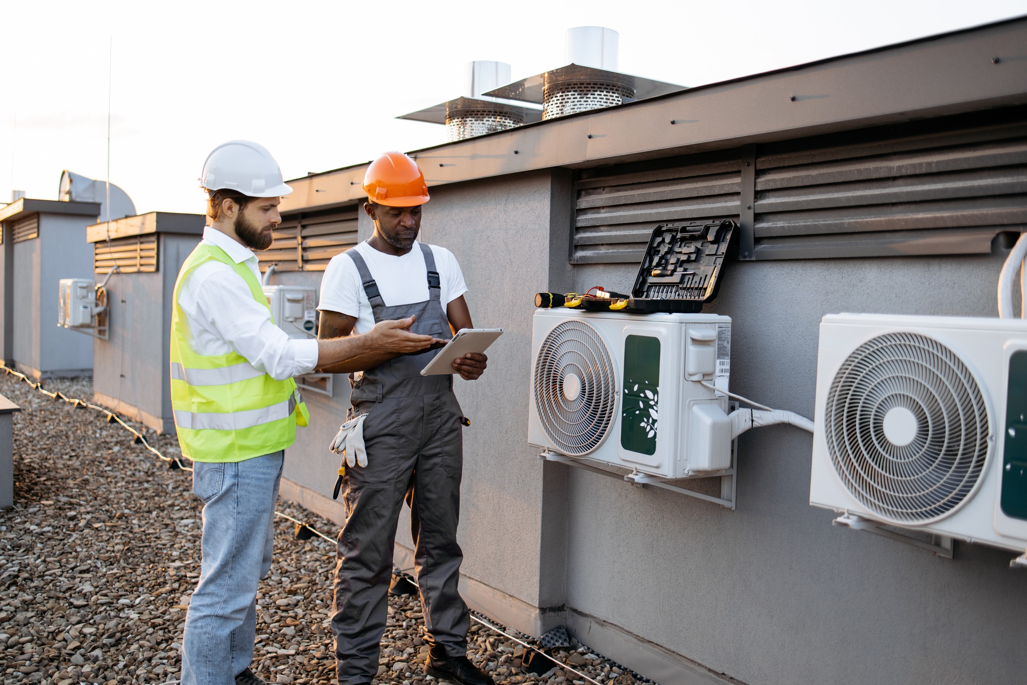 Multicultural males repairing air conditioner using tablet